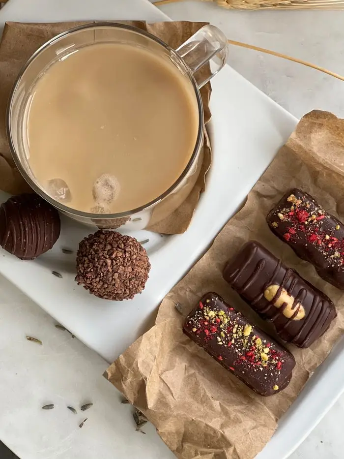 Delicious gourmet chocolate treats and a cup of coffee arranged on a tray for an elegant afternoon snack.
