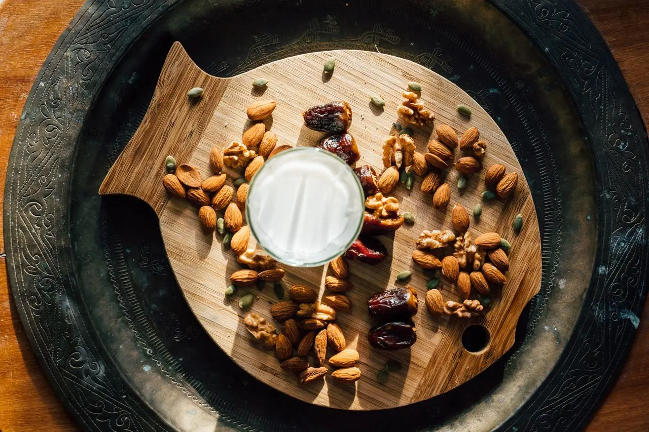 Aerial view of mixed nuts, dates, and glass of milk on a fish-shaped wooden platter. Perfect for healthy living concepts.